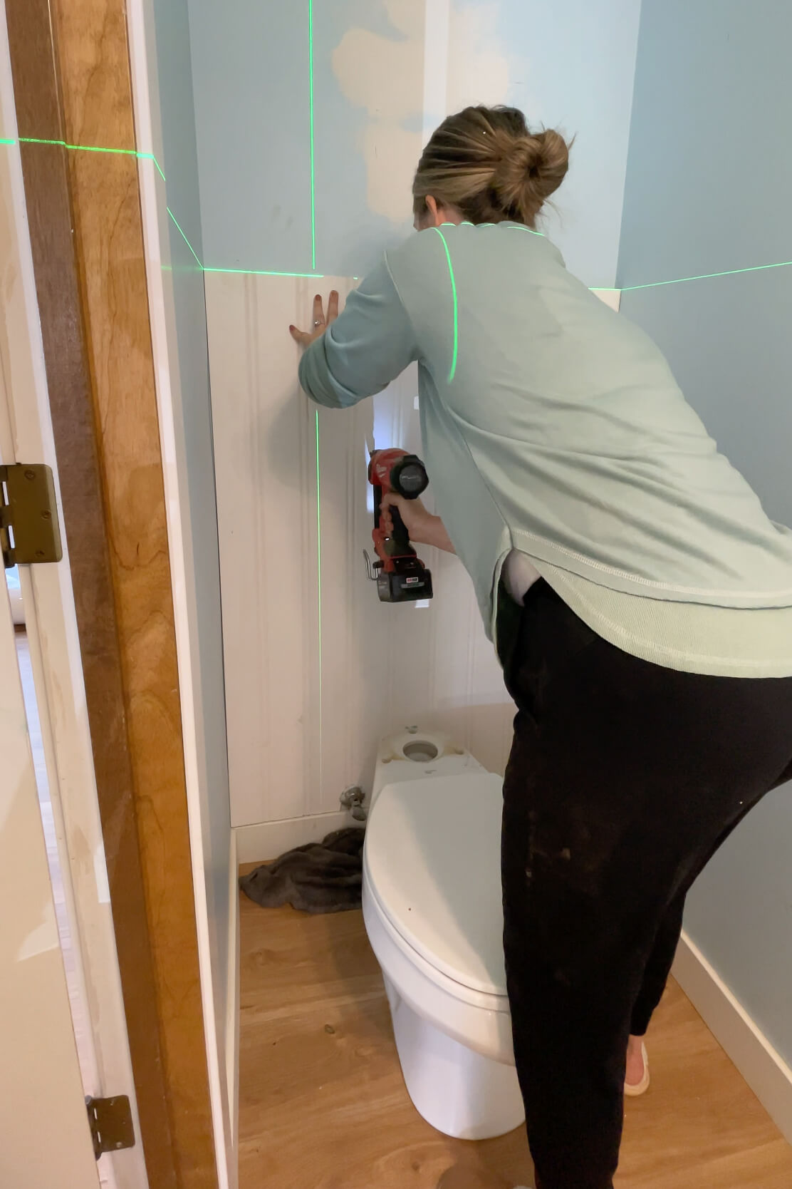 Using a brad nailer to attach beadboard to a bathroom wall.